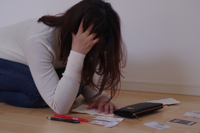 お金を手に頭を抱える。伊丹市で債務整理の無料相談が弁護士にできます